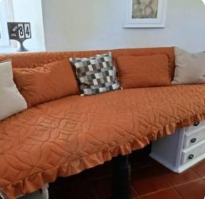 un sofá naranja con dos almohadas encima en Windmill House, en Encarnação