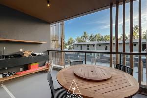 a dining room with a wooden table and a balcony at Flats Beira-Mar na Rota dos Milagres - Essence Tatuamunha in Pôrto de Pedras