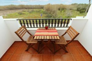 Una mesa y dos sillas en un balcón. en Casa Papoila T1 com terraço, en Vila Nova de Milfontes