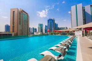 a swimming pool with chaise lounge chairs and a city skyline at Downtown Panoramic View in Dubai