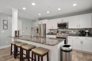 een keuken met witte kasten en een bar met barkrukken bij NH387 Haven on the Banks in Nags Head