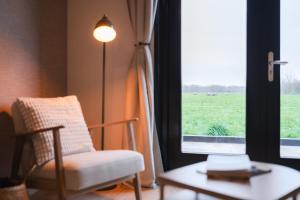 a room with a chair and a window with a view of a field at Vakantiehuis Blok 25 in Zierikzee