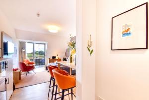 a kitchen and living room with orange chairs and a table at Ferienwohnung Grasmücke 09 im Wreecher Idyll Rügen by ruyastay in Putbus +5 photos