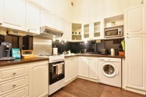 a kitchen with white cabinets and a washer and dryer at Karlsbad Holiday in Karlovy Vary