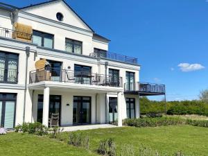 une maison blanche avec des balcons et une cour dans l'établissement Ferienresidenz Haus Vogelflug Fehmarn-Ostseeferien Strandresidenz Vogelflug 141 App 4 Meerblick, à Fehmarn 13 autres photos