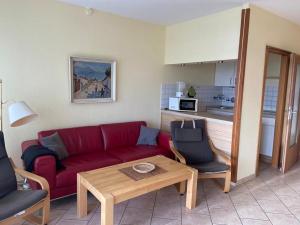 a living room with a red couch and a table at FeWo Schulze in Fehmarn
