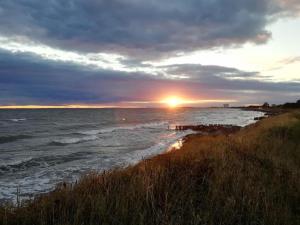 a sunset over the ocean with the sun setting at FeWo Schulze in Fehmarn