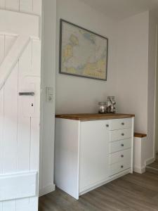 a room with a white dresser with a map on the wall at Kleine Meerjungfrau in Fehmarn +15 photos