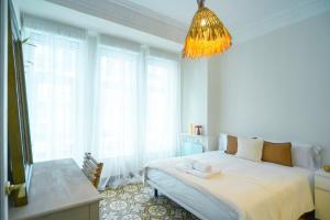 una camera da letto bianca con un letto e un lampadario di Apartamento Matilde a Ferrol