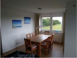 a dining room table with chairs and a large window at Seeblick in Fehmarn