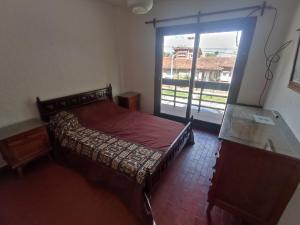 a bedroom with a bed and a large window at Departamento céntrico en Miramar in Miramar