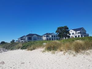 une rangée de maisons au sommet d'une plage dans l'établissement Ferienresidenz Haus Vogelflug Strandresidenz Vogelflug App 10, à Fehmarn