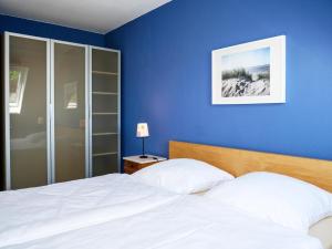 a bedroom with blue walls and a bed with white sheets at Ferienwohnung Küthe in Fehmarn