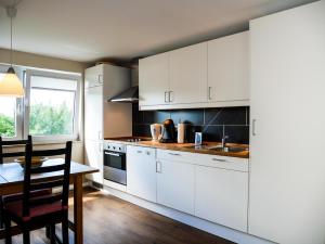 a kitchen with white cabinets and a table and a window at Ferienwohnung Küthe in Fehmarn
