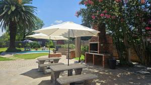 two picnic tables with an umbrella and a grill at Bosveld In Die Stad 2 Guesthouse in Alberton