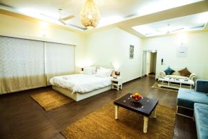 a bedroom with a bed and a couch and a table at Anara Service Apartments - Greater Kailash Part II in New Delhi