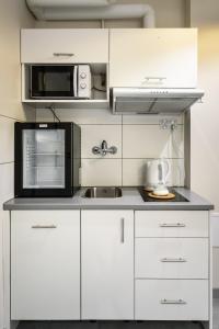 cocina con armarios blancos y microondas negro en Polmedica Nowoogrodzka A, en Varsovia