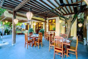 a restaurant with a table and chairs and a tree at Thanh Van 1 Hotel in Hoi An
