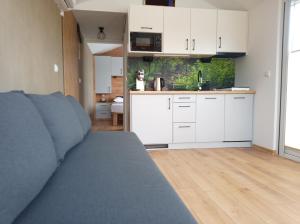 a kitchen with white cabinets and a couch in a room at Domek Przystań na Grapie in Nowa Biała