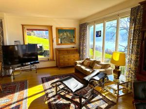 a living room with a couch and a flat screen tv at SwissHut Stunning Views Alps Lake - Chalet Chrutzwag in Sigriswil +29 photos