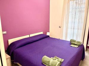 a bedroom with a purple bed and a window at Casa Violetta in Alba