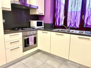 a kitchen with white cabinets and purple walls at Casa Violetta in Alba