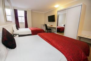 a hotel room with two beds and a desk at Isa Hotel in Mount Isa