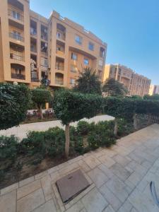 un grande condominio con una siepe in un cortile di TREE Serviced Apartment -2BHK Self check-in a Il Cairo