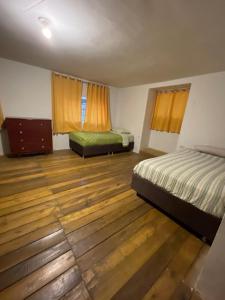 a bedroom with two beds and a wooden floor at Casa de campo larespampa in Urubamba
