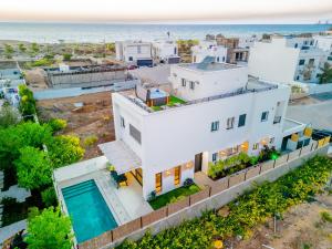 an aerial view of a white house with the ocean in the background at לגונה בלו ביץ-וילה מהממת עם בריכה פרטית וג'קוזי דקה מהים in H̱adera