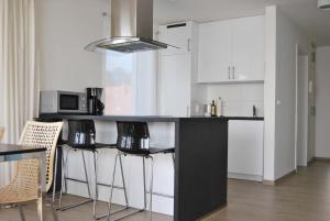 a kitchen with white cabinets and a black counter with stools at Ferienresidenz Haus Vogelflug Strandresidenz Vogelflug App 17 in Fehmarn