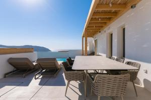 a patio with a table and chairs on a balcony at Villa Vibe B - Hot tub - MG Villas in Mýkonos City +44 photos