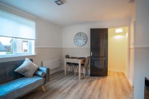 een woonkamer met een tafel en een klok aan de muur bij 1 BDR Apartment At Caledonia Luxe Stays Short Lets & Serviced Accommodation Airdrie in Airdrie