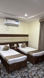 a hotel room with two beds and a tv at نزل وريف المقام للايواء السياحي in Makkah