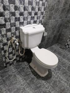 ein Badezimmer mit einer weißen Toilette in einer gefliesten Wand in der Unterkunft Green rooms in Weligama