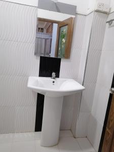 ein Badezimmer mit einem weißen Waschbecken und einem Spiegel in der Unterkunft Green rooms in Weligama