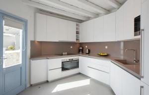 una cucina con mobili bianchi e un lavandino di Marvelous 7 BR Villa Overlooking the Psarou Bay a Psarou