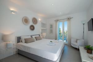 una camera da letto bianca con un letto grande e una sedia di Marvelous 7 BR Villa Overlooking the Psarou Bay a Psarou Altre 21 foto