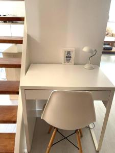 a white desk with a chair and a lamp at The Beach House in Noordwijkerhout