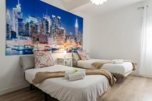 a room with two beds and a painting of a city at Casa Mario Suites in Santa Cruz de Tenerife