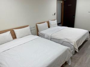 two beds sitting next to each other in a room at Boyun Hostel in Kaohsiung