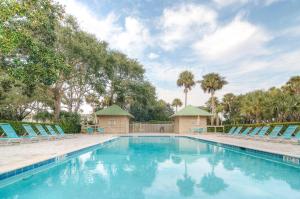 a swimming pool with blue chairs and trees at AB15: 15 Atlantic Beach in Kiawah Island