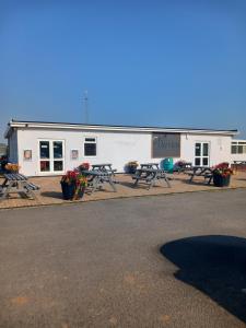 a white building with picnic tables in front of it at Cozy caravan in Mablethorpe in Mablethorpe
