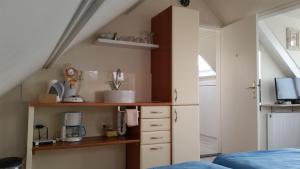 a room with a shelf and a kitchen in a attic at Homestay Texel in Den Burg