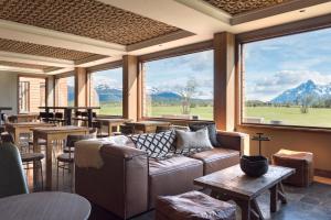 a lobby with a couch and tables and windows at Río Serrano Hotel + Spa in Torres del Paine