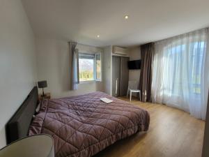 una camera da letto con un letto grande e una finestra di Résidence Andurans - Pyrénées Resort ad Argelès-Gazost