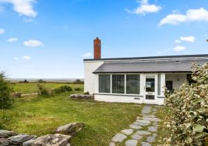 a small white house with a brick chimney on top at Camelot, Newport - A Pembrokeshire Waterside Cottage in Newport Pembrokeshire
