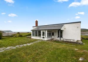 a small white house with a grass yard at Camelot, Newport - A Pembrokeshire Waterside Cottage in Newport Pembrokeshire
