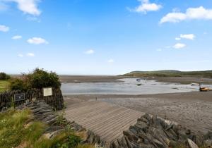 a sandy beach with a wooden walkway to the beach at Camelot, Newport - A Pembrokeshire Waterside Cottage in Newport Pembrokeshire