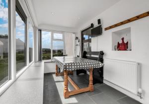 a dining room with a table and some windows at Camelot, Newport - A Pembrokeshire Waterside Cottage in Newport Pembrokeshire